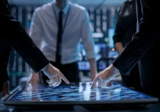 A photo of people standing around a smart table.