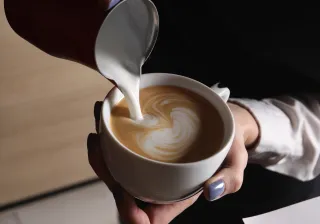 Someone pouring milk to coffee