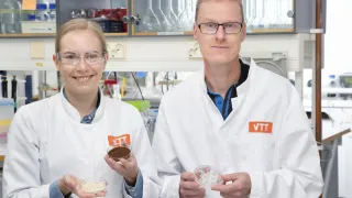 Two researchers smiling at the camera wearing VTT lab coats