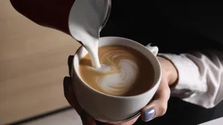 Someone pouring milk to coffee