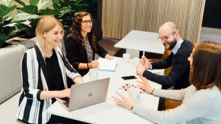 illustrative image of people sitting around a table in an office setting