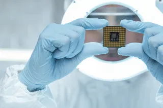 A closeup of a cleanroom lab worker&#039;s hands holding a computer chip