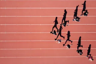 A photo of a group of runners running on a track field.