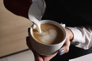 Someone pouring milk to coffee