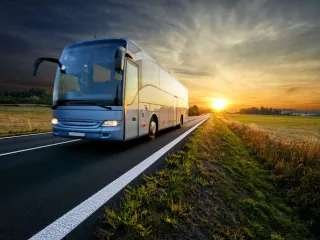 A bus is driving down the road at sunset